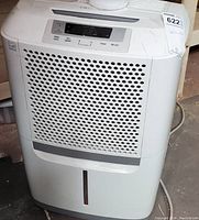 Frigidaire white dehumidifier front view showing perforated air intake grille, top control panel and water level indicator strip.