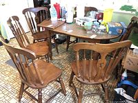 Set of six vintage wood dining chairs shown around a rectangular table, placed in a kitchen setting with linoleum flooring.