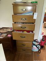 Front view of the six drawer wooden lingerie chest with some drawers open revealing linens inside, brass handles, and surface scratches.