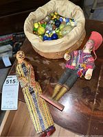 Overall view of two artisan dolls and a cloth sack full of vintage marbles on a table