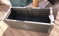 Top view of a rectangular outdoor planter box showing inside base with drainage holes and the weathered resin construction designed to look like wood.