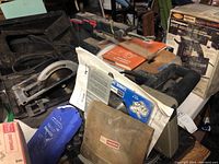 Craftsman power tools and accessories displayed on workbench with packaging and manuals. Includes blue traveler hammock bag, nut driver set in beige case, compound miter saw partially visible, and boxed pad sander.