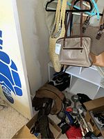 Overview of purses and bags hanging on hangers with shoes and boots below