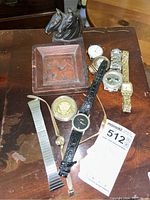 Photo showing five wristwatches, two extra watch bands, a wooden trinket holder with horse heads, and the Seal of the President medallion.