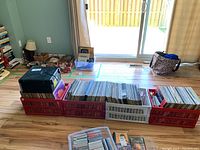 Wide shot of four plastic crates filled with vinyl records and a plastic bin with CDs in a living room.