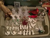 Photo of assorted angel and dove Christmas figurines, cardinal bird figurines, and other assorted holiday decorations inside green bin.
