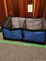 Front view of blue and gray divided car container showing two large compartments and black edging.