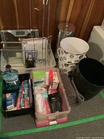 Bathroom items including Health O Meter scale, chrome towel and toilet roll holder, waste baskets, pharmacy products in trays and bath mat.