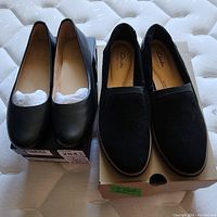 Two pairs of ladies shoes: Naturalizer black low heel shoes on left and Clarks black slip-on loafers on right, both size 9M, appear new.