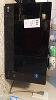 Top and front angle black LG microwave on granite counter with price tag.