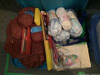 Photo showing skeins of yarn in various colors, knitting needles, and other knitting supplies in a blue bin.