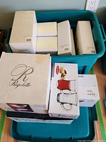 Stacked boxes including Rigoletto martini glass packaging and other glassware box sets in a blue container.