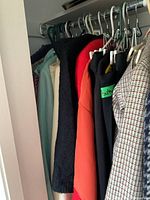 Clothes hanging on a rod, assortment of jackets and blazers in various colors including black, red, aqua, orange, beige, and patterns.