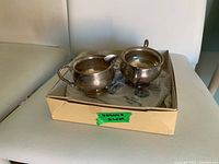 Set of two small weighted sterling silver cream and sugar containers in a box with a label 'Weighted Silver'.