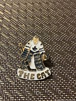 Close-up of a metal enamel pin depicting a hockey goalie in Toronto Maple Leafs jersey with 'THE CAT' text