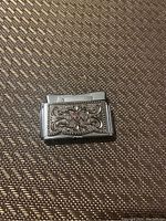 Front view of Fischer lighter showing intricate floral embossed design and red gem