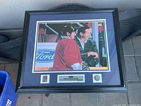Framed hockey photo showing player and man with Ford logo in background, with medallions and plaque below.