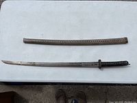 Full view of sword and scabbard laid flat on table.