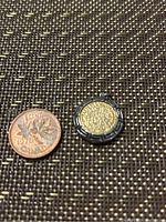 Close-up photo comparing pendant with Canadian one-cent coin for size reference. Shows front of the pendant with gold-colored coin inside silver frame.