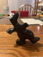Front angle of black soapstone bear figurine showing upright pose with outstretched arms and facial details.
