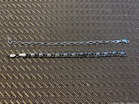 Two sterling silver bracelets displayed side by side on dark textured surface, showing full length of chain link bracelet and patterned S-shaped bracelet.