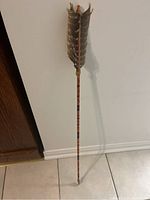 Full view of the wooden arrow with feather fletching and stone tip