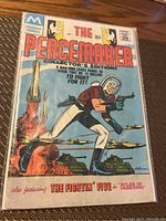 Photo of the front cover of The Peacemaker Comic Issue #1 showing colorful vintage comic art with main character and military vehicles.