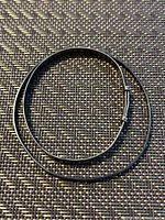 Photo of two sterling silver bracelets laid flat on woven textured surface showing smooth and patterned designs.