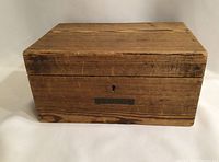 Front view of aged wooden box with brass nameplate showing 'T. Upton'.