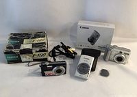 Three cameras displayed with original boxes and cables