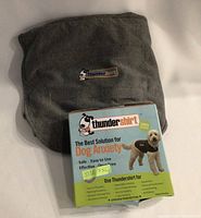 Thundershirt folded gray fabric with informational packaging card showing the product name and a dog wearing the shirt.