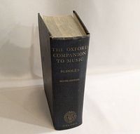 Spine view of The Oxford Companion to Music showing gold embossed title, author Scholes, edition number, and Oxford emblem on navy blue cover.