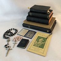 Photo showing full lot with stacked vintage books, two rosaries, devotional medals card, and Saint Philomena booklet