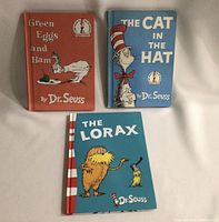 Three Dr. Seuss books laid flat: Green Eggs and Ham, The Cat in the Hat, and The Lorax.