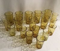 All 18 glasses grouped showing 8 tumblers and 10 juice glasses in amber with Hazel Atlas El Dorado circular bubble pattern.