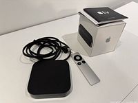 Overall lot including Apple TV device, remote control, power cable, manual, and original box displayed on a white surface.
