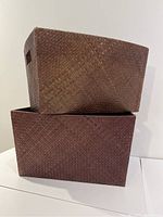 Two large rectangular woven baskets stacked one inside the other, showing the textured weave pattern and rectangular cuts handles.