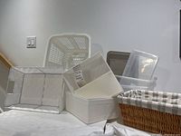 Overview of all baskets and bins showing plastic bins, laundry baskets, lined wicker basket, IKEA fabric organizers, and woven basket.