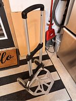 Folding hand cart extended with visible handle and base plate, showing the wheels and design details.