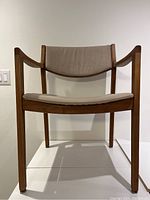 Front view of the walnut midcentury modern armchair showing upholstered seat and backrest within angular wooden frame.