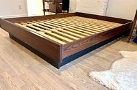 Side view of assembled bed frame showing dark rosewood finish and black base plinth