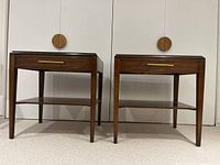 Front view of two matching mahogany veneer end tables with gold drawer handles.