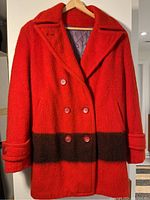 Front view of vintage red wool coat with double-breasted buttons and dark brown band near hem
