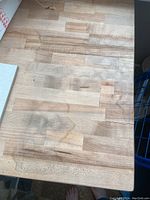 Close up of butcher block wooden top showing patchwork wood grain and some surface marks.