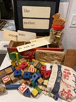 Full view of the collection showing letter stamps, word cards, wooden blocks, a small jar with stamps, and carving molds arranged on and around a wooden crate.