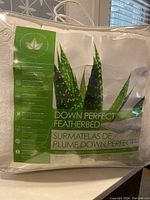 Front view of the down featherbed packaging showing brand and product details like Down Perfect featherbed, down pillow top design, and aloe leaf image.