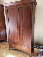 Front view of closed armoire showing double doors and base drawers