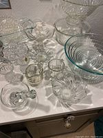 Vintage collection of glass and crystal mixing bowls, candle holder, mortar and pestle, and decorative serving dishes on a countertop showing used condition but good shape