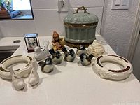 Overall lot showing five bluebird figurines, Hummel Chick Girl, white ceramic pieces, and large pale green ceramic box with handle.