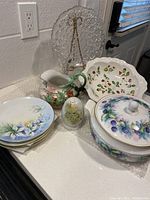 Photo showing all porcelain pieces including covered dish, plates, pitcher, bowl, figurine, and glass plate stand.